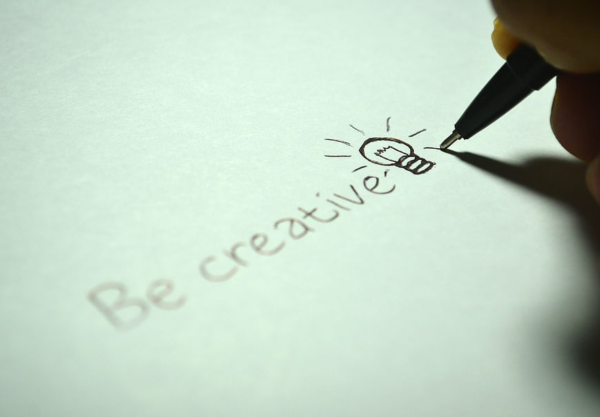 Hand writing be creative with lightbulb icon on paper