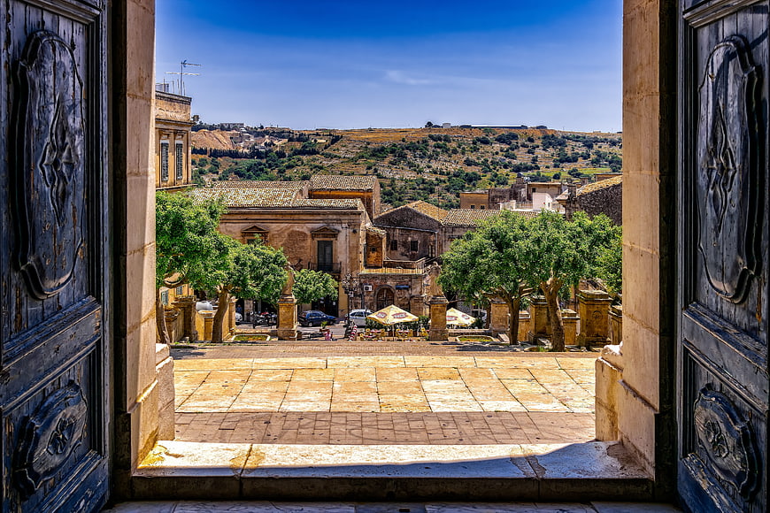 View of Modica, Sicily through open wooden church doors