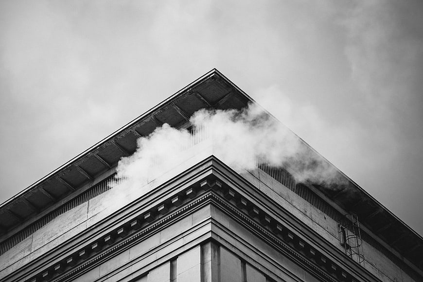Black and white photo of steam rising from a building corner