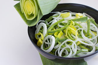Fresh sliced leeks in a black bowl with decorative garnish