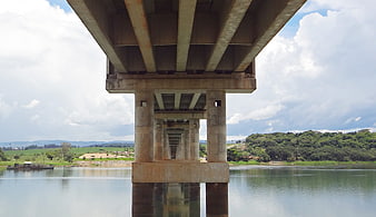 Underneath concrete bridge pillars over river landscape