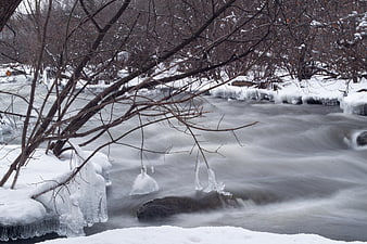 Winter river flowing through snowy forest with ice formations