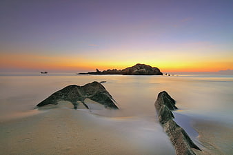 Long Exposure Sunset Beach with Silhouetted Rocks and Misty Ocean