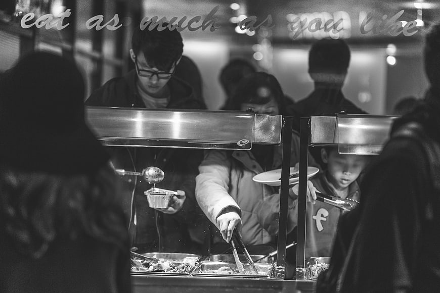 Black and white photo of people serving food at a buffet