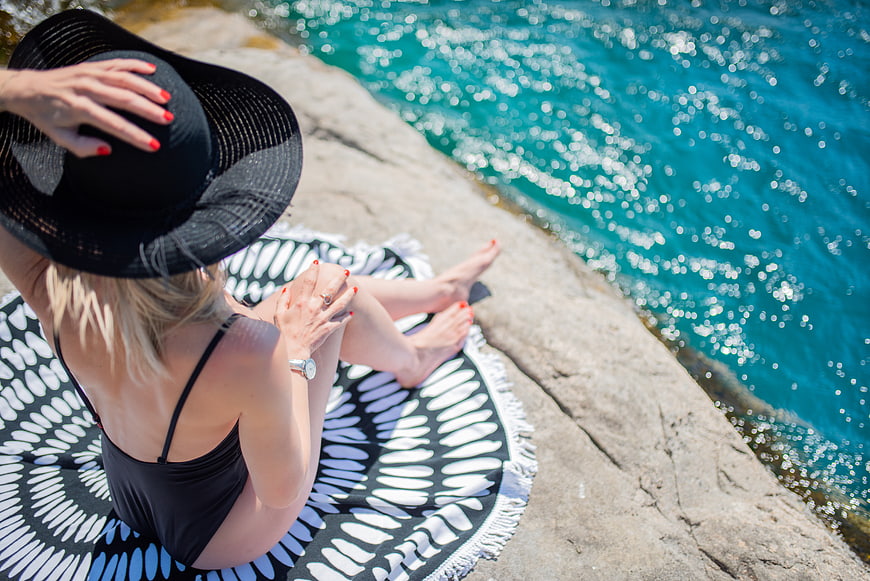 Woman in black swimsuit relaxing on rocky beach
