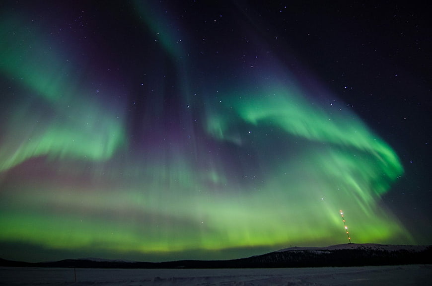 Vibrant green aurora borealis over snowy arctic landscape