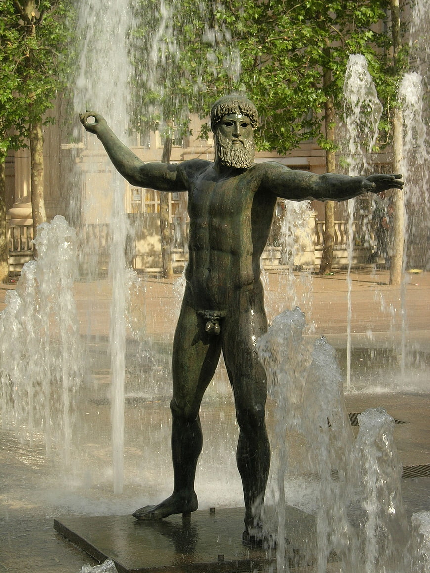 Bronze male statue in urban fountain with water jets