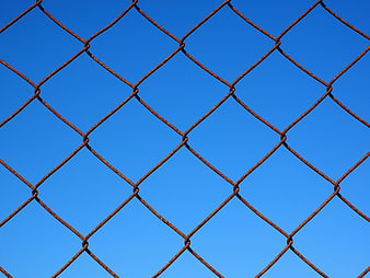 Rusty Chain Link Fence Against Blue Sky Background