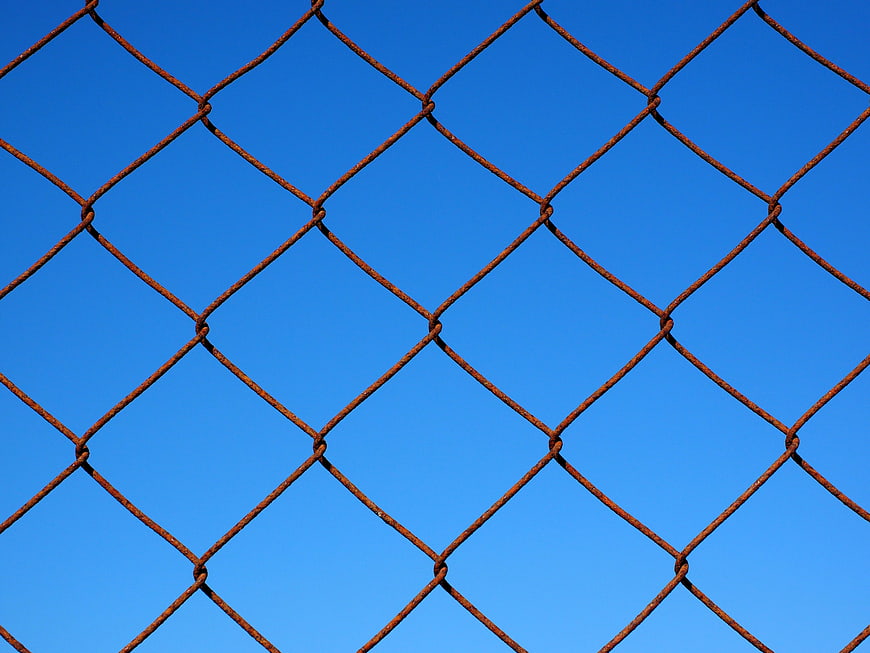 Rusty Chain Link Fence Against Blue Sky Background