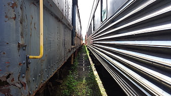 Rusty train car and modern passenger train in narrow railway corridor