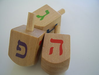 Wooden dreidels with Hebrew letters on white background