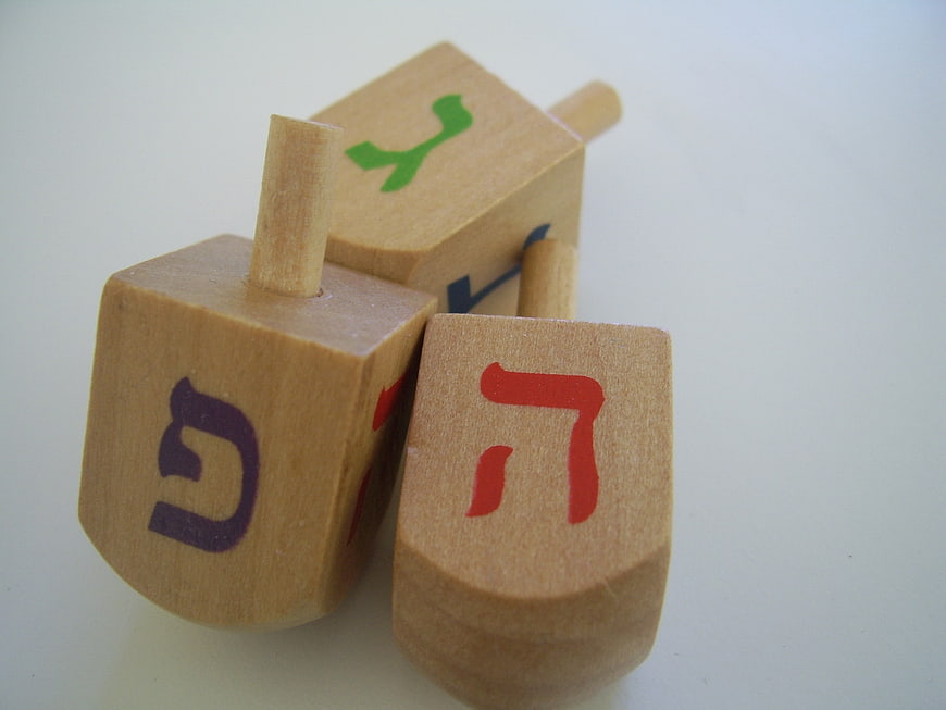 Wooden dreidels with Hebrew letters on white background
