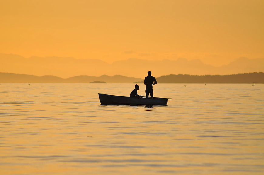 Silhouette of Two People in a Boat at Golden Sunset