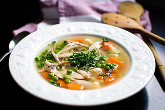 Homemade chicken soup with vegetables in white bowl