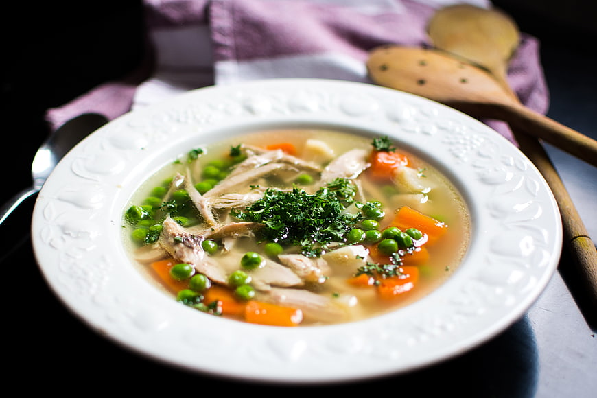 Homemade chicken soup with vegetables in white bowl