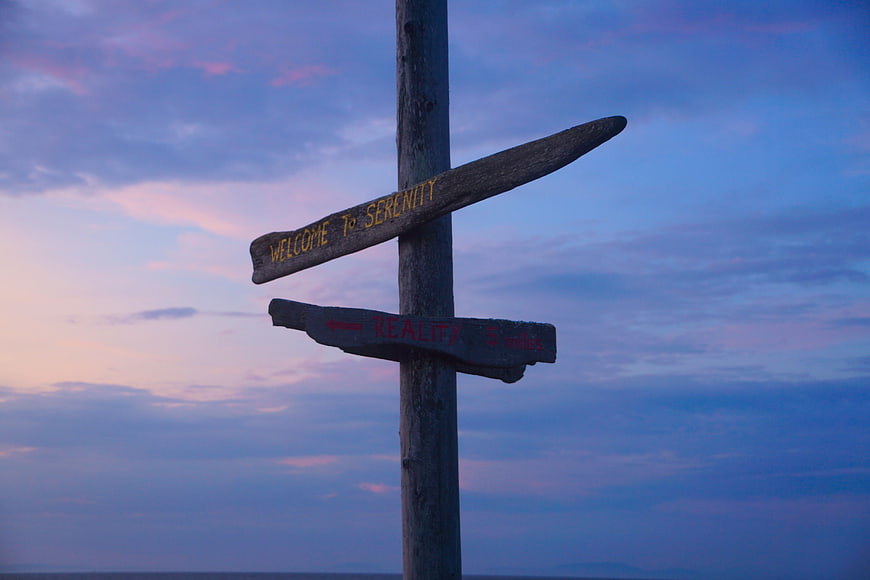 Wooden Signpost Reading Welcome to Serenity and Reality at Sunset