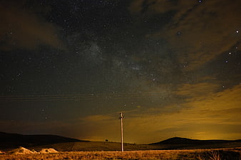Milky Way night sky over rural landscape with utility pole