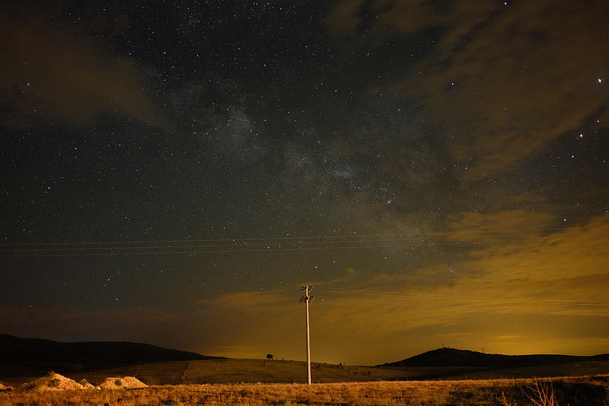 Milky Way night sky over rural landscape with utility pole