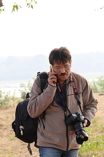 Photographer talking on phone outdoors with DSLR camera