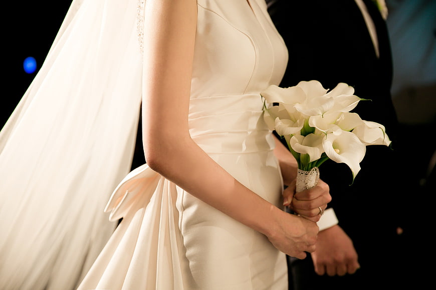 Bride holding white calla lily bouquet in wedding dress