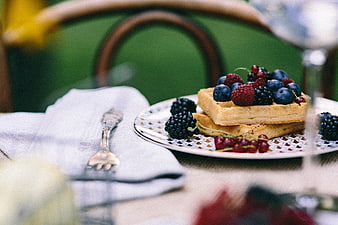 Stacked waffles with fresh berries on a vintage plate outdoors