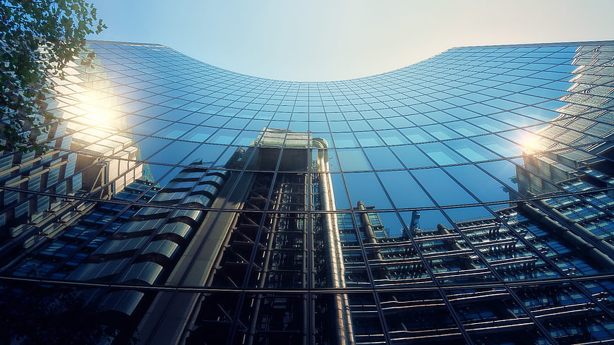 Low angle view of modern glass skyscraper with sun flare