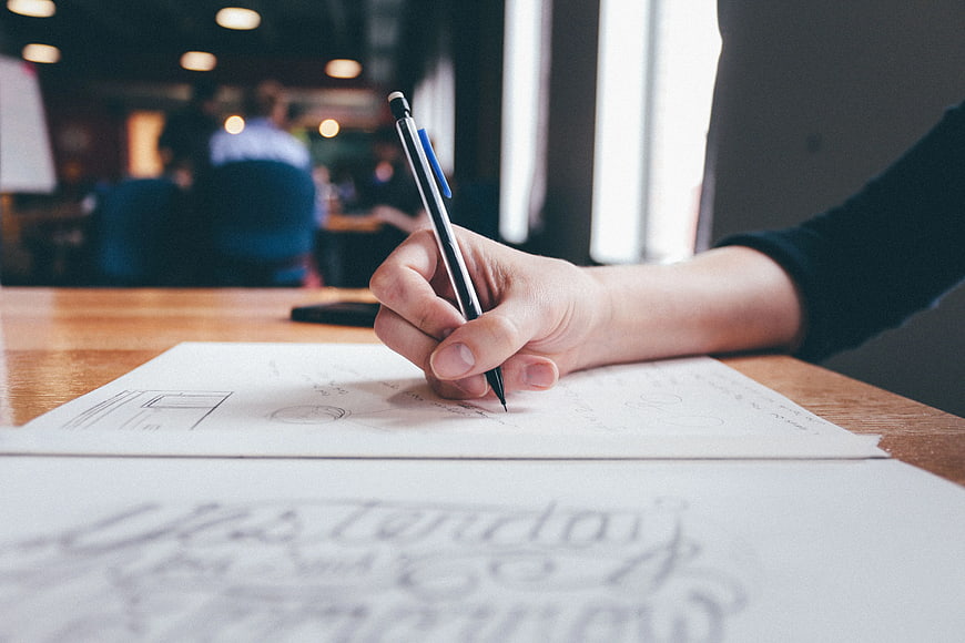 Hand sketching wireframes on paper in office workspace
