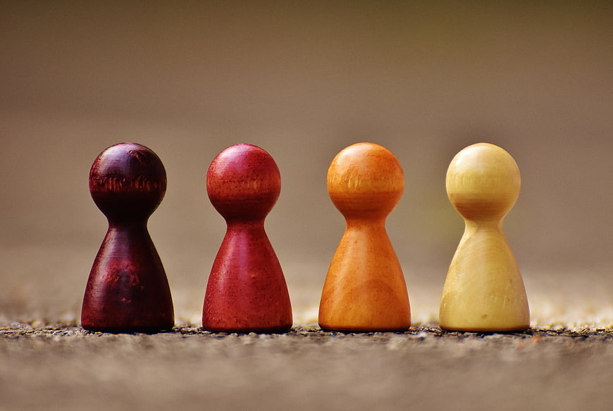 Four colorful wooden chess pawns standing in a row on a textured surface