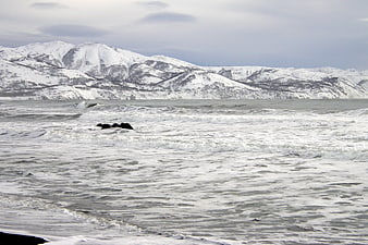 Snowy Mountains and Icy Ocean Waves in Winter Landscape