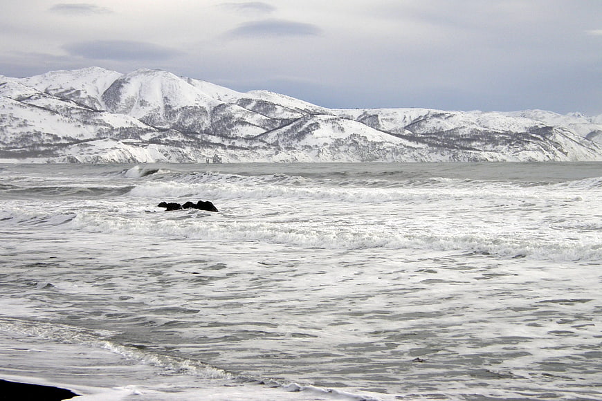 Snowy Mountains and Icy Ocean Waves in Winter Landscape