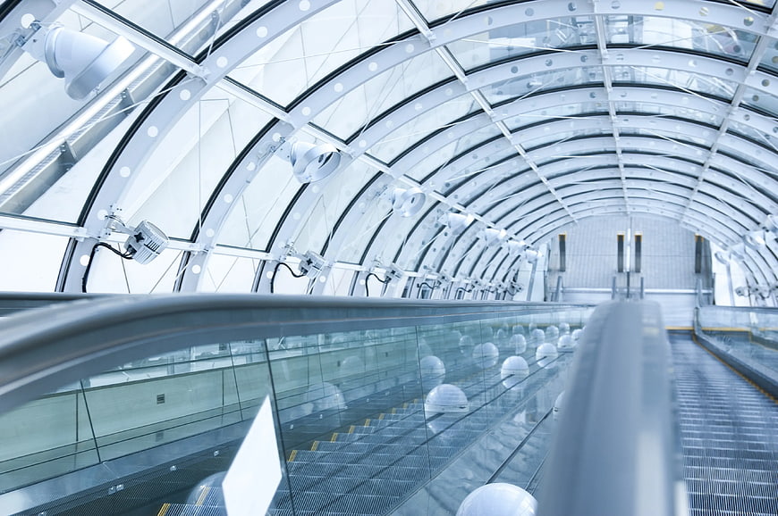 Modern glass escalator tunnel with curved ceiling architecture