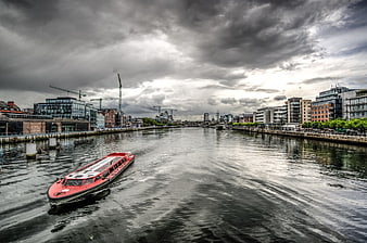 Red tour boat on River Liffey in Dublin under dramatic clouds