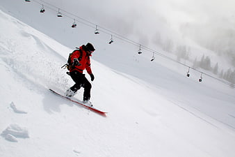 Snowboarder in Red Jacket Carving Down Snowy Mountain Slope