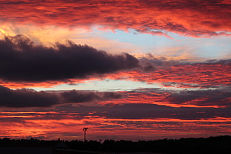 Dramatic fiery red sunset sky with dark clouds and silhouette