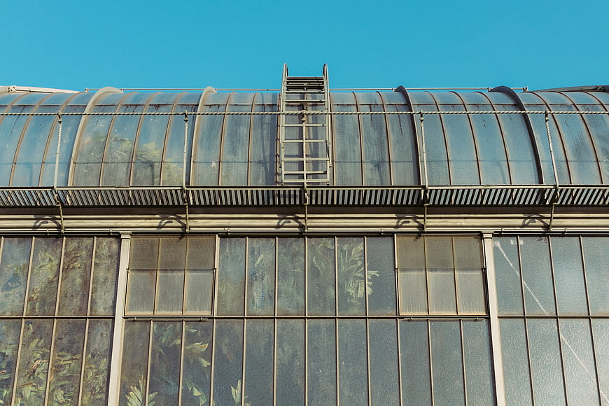 Industrial greenhouse roof with metal ladder and blue sky