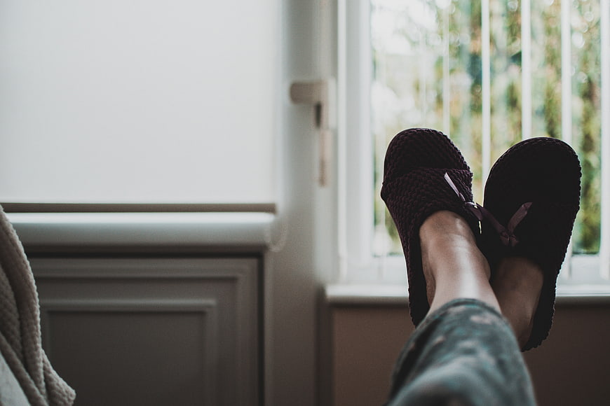 Relaxed Woman's Feet in Slippers by Window
