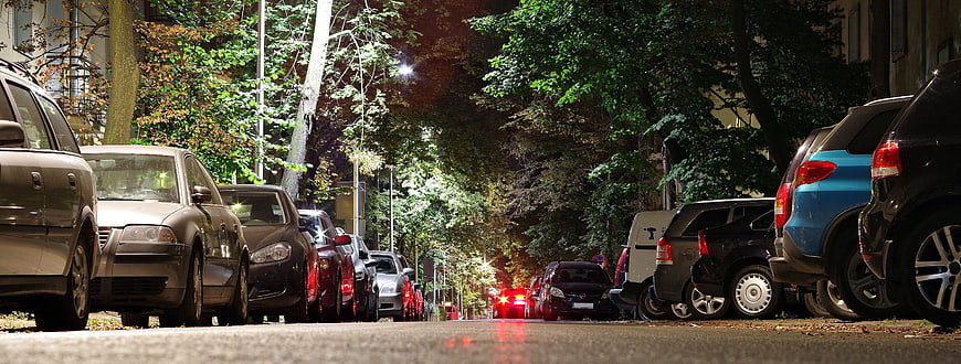 Nighttime street view with parked cars and trees