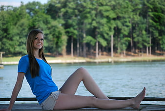 Young woman sitting on a wooden dock by a lake