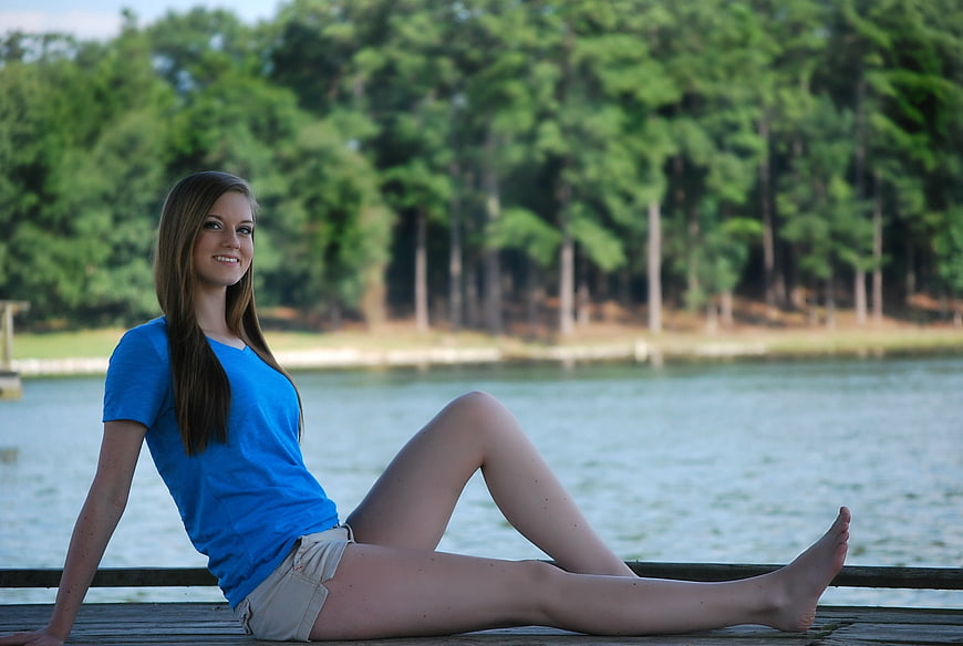 Young woman sitting on a wooden dock by a lake