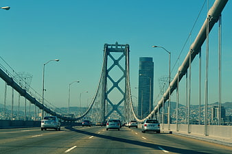 Cars driving on suspension bridge with city skyline