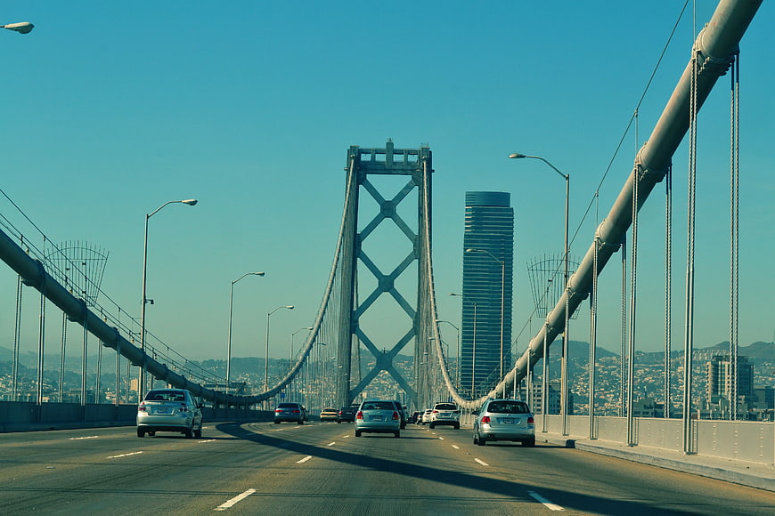 Cars driving on suspension bridge with city skyline