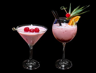 Two pink fruit cocktails with cherry and citrus garnish on black background