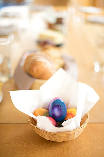 Colorful Easter Eggs in Wicker Basket on Wooden Table