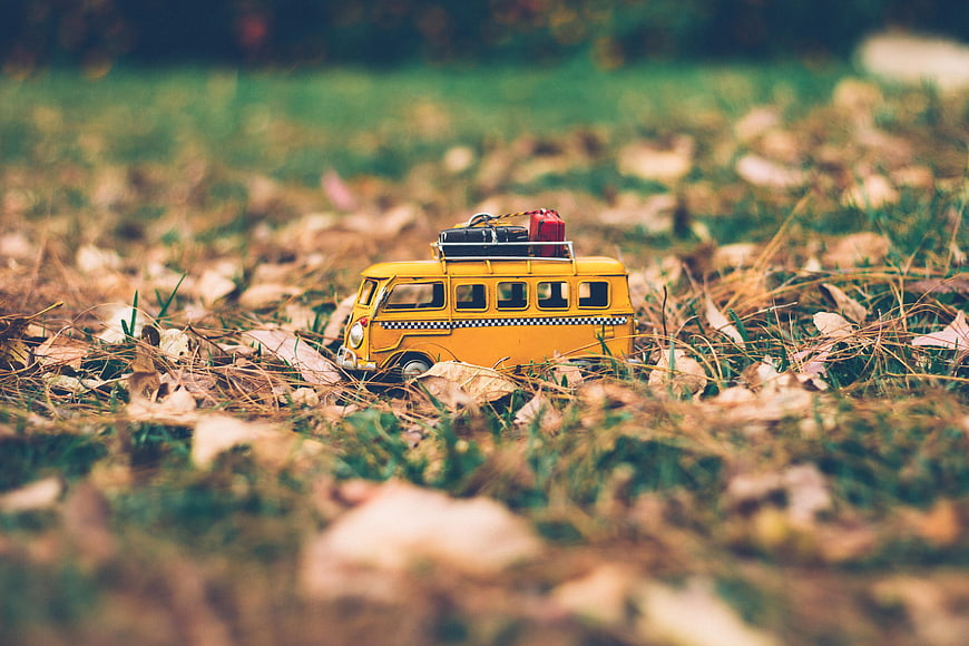 Yellow toy bus with luggage on autumn grass