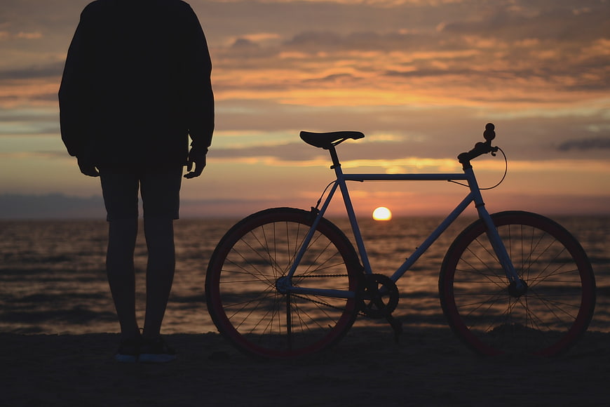 Silhouette of Man and Bicycle at Sunset on Beach