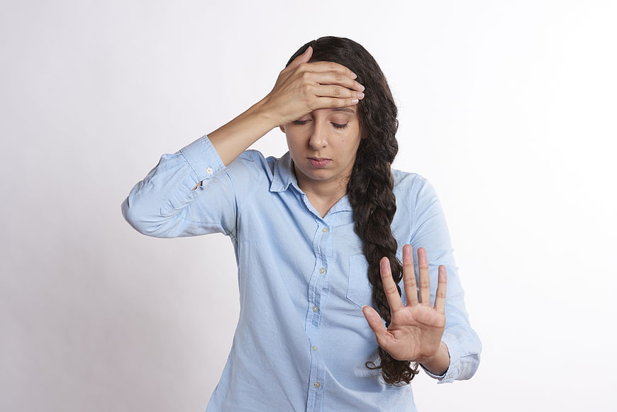 Stressed woman holding head and hand in stop gesture