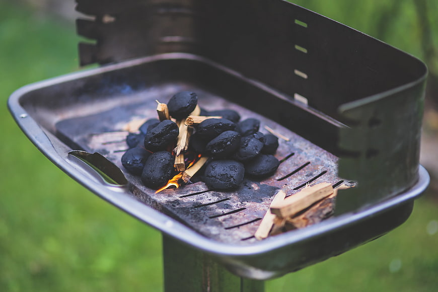 Charcoal briquettes igniting in a portable camping grill