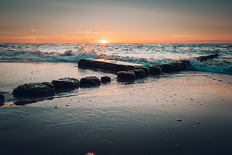 Sunset over ocean waves crashing on rocky beach