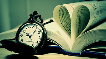 Vintage pocket watch on open book with heart-shaped pages