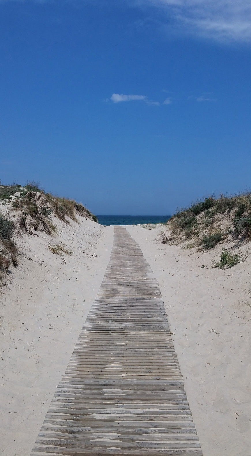 Wooden Boardwalk Path Through Sand Dunes to Blue Ocean